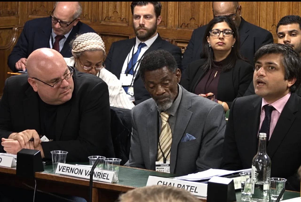 AI-upscaled still of Vernon Vanriel seated at the Public Accounts Committee hearing on the Windrush generation and the Home Office.